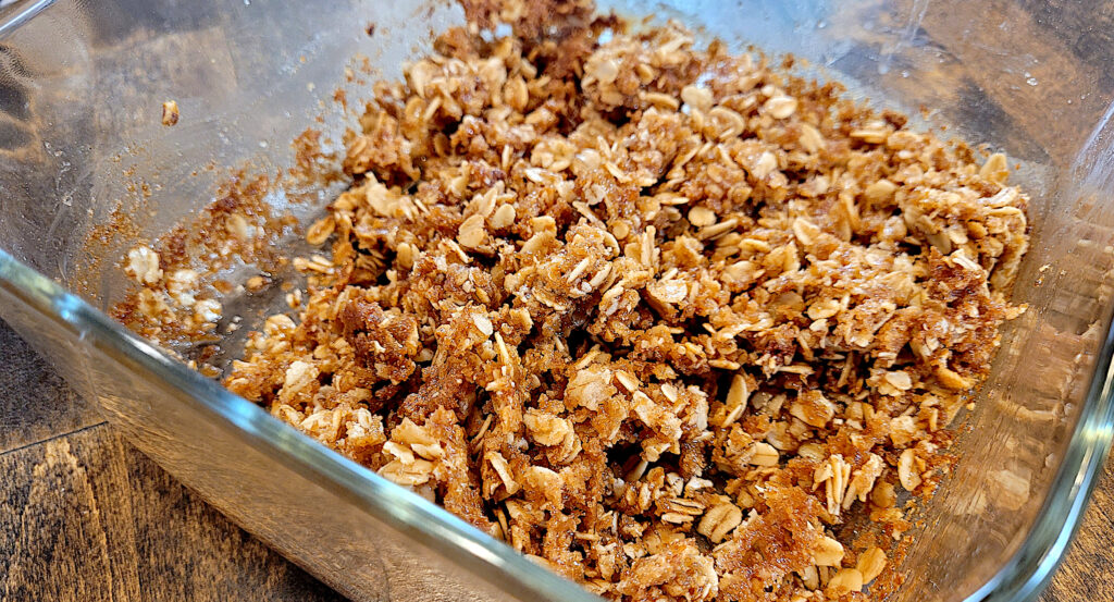 oat filled crisp topping in a glass baking dish on a butcher block countertop