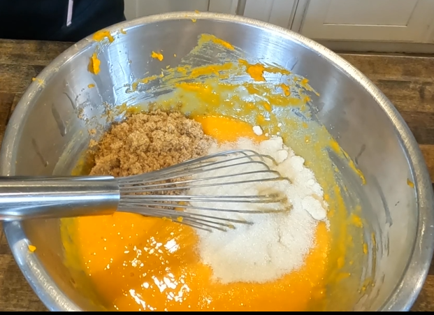 butternut squash bread batter with granulated sugar and brown sugar in a stainless steel bowl with a whisk