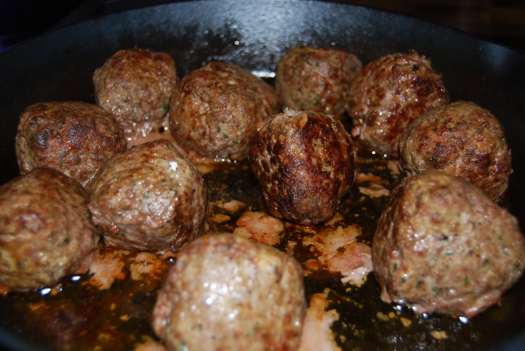 Completely browned meatballs in a cast iron pan