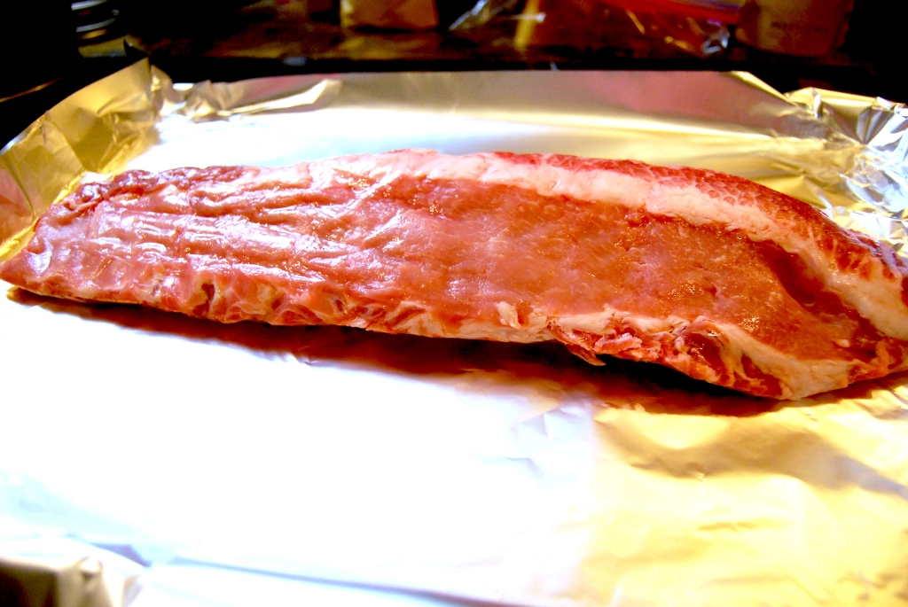 Rack of spare ribs on an aluminum foil covered baking sheet