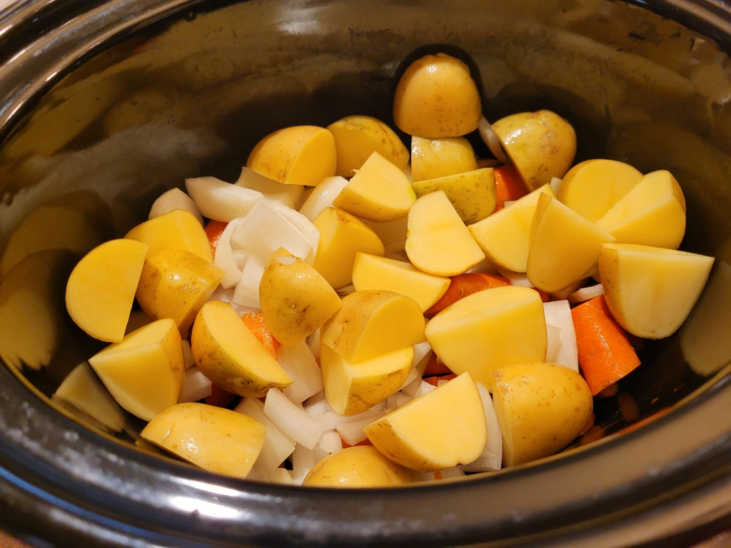 onions, potatoes, and carrots chopped in slow cooker