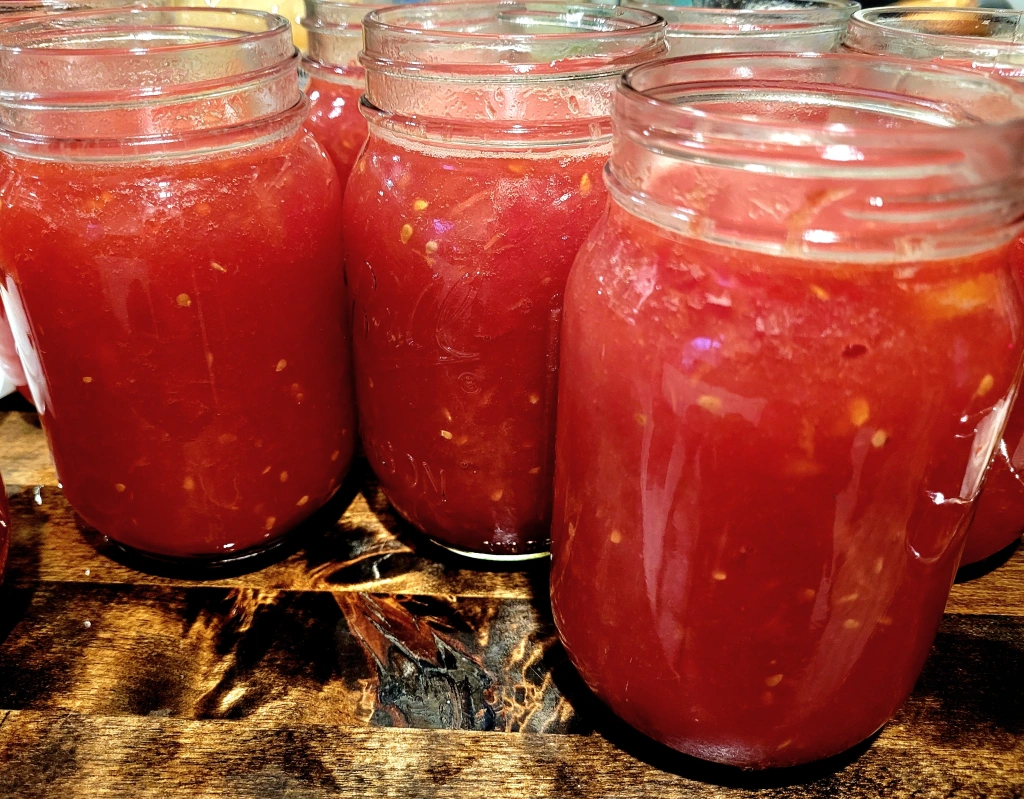Jars of crushed tomatoes without lids on butcher block counter