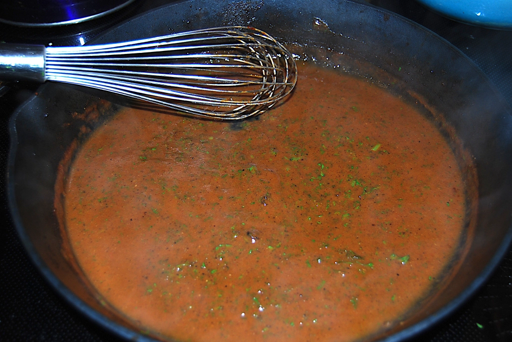 red wine sauce in a cast iron skillet with a metal whisk
