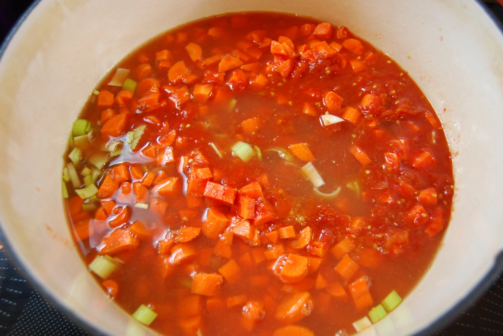 chopped vegetables in broth in an enamel coated cast iron pot