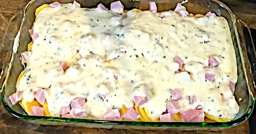scalloped potatoes with 2 layers of cream sauce and ham in glass 9x13 baking dish