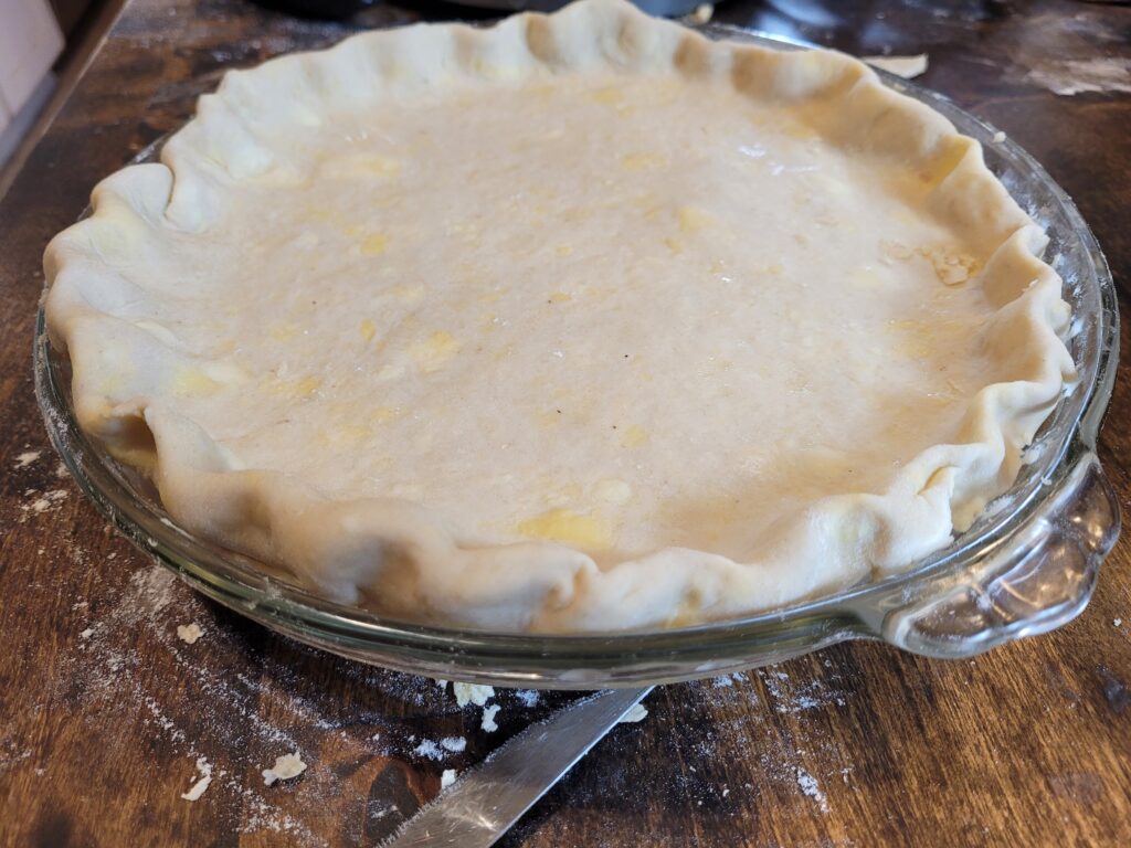 Uncooked pie in glass baking dish on butcher block counter