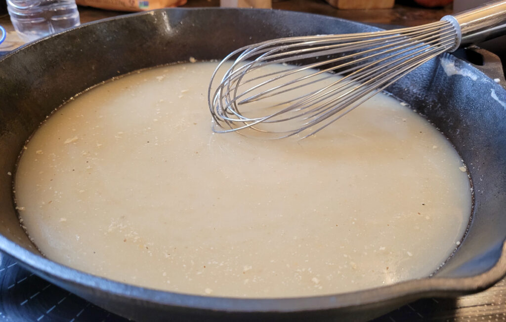 thickening broth in cast iron skillet with wire whisk