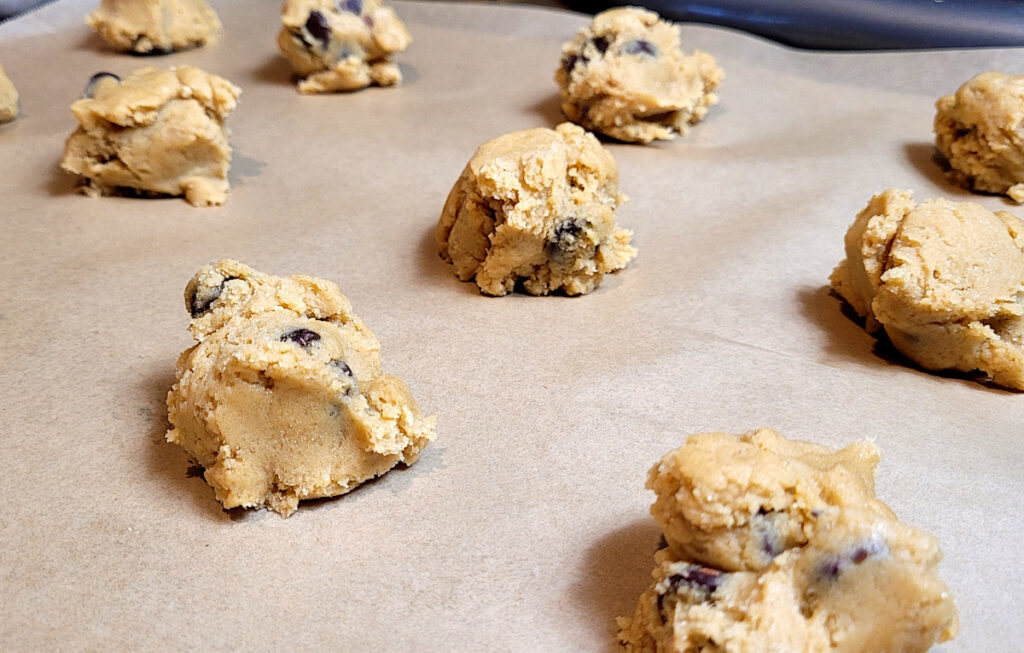 uncooked chocolate chip cookies on parchment paper lined baking sheet