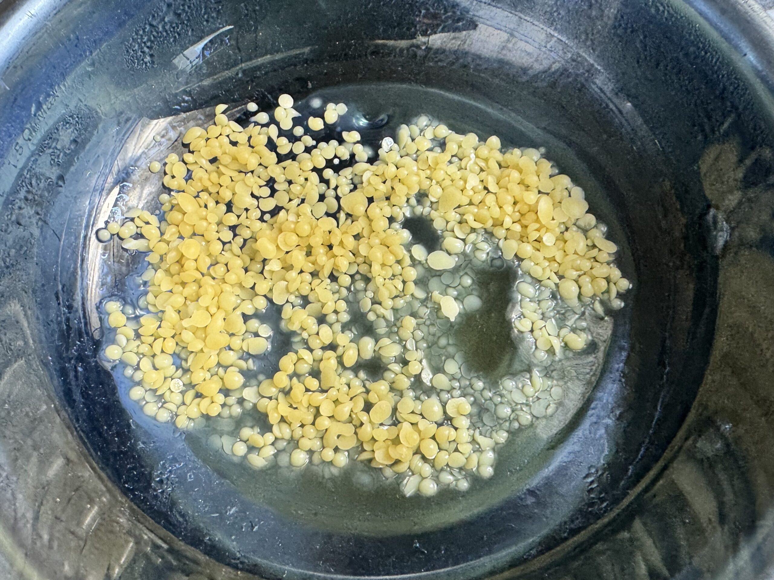 beeswax pellets melting in a glass bowl