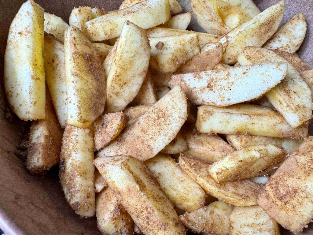 cinnamon covered apple slices in a brown bowl