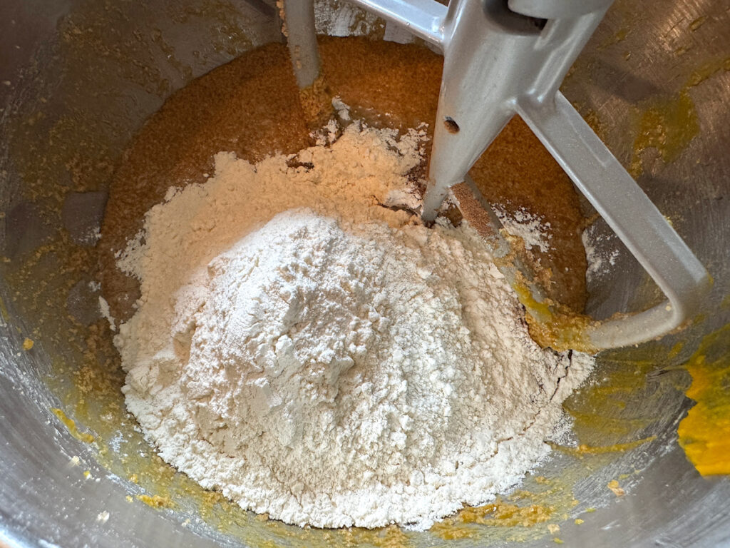 flour and other dry ingredients added to batter in a stainless steel mixing bowl