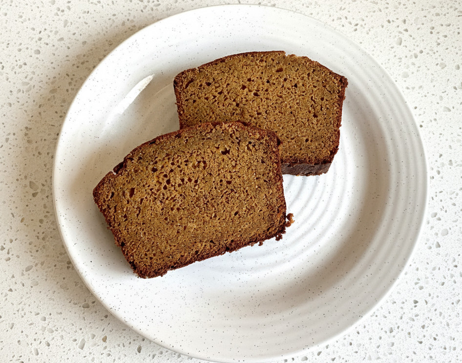 two slices of pumpkin bread with apple cider on a white plate