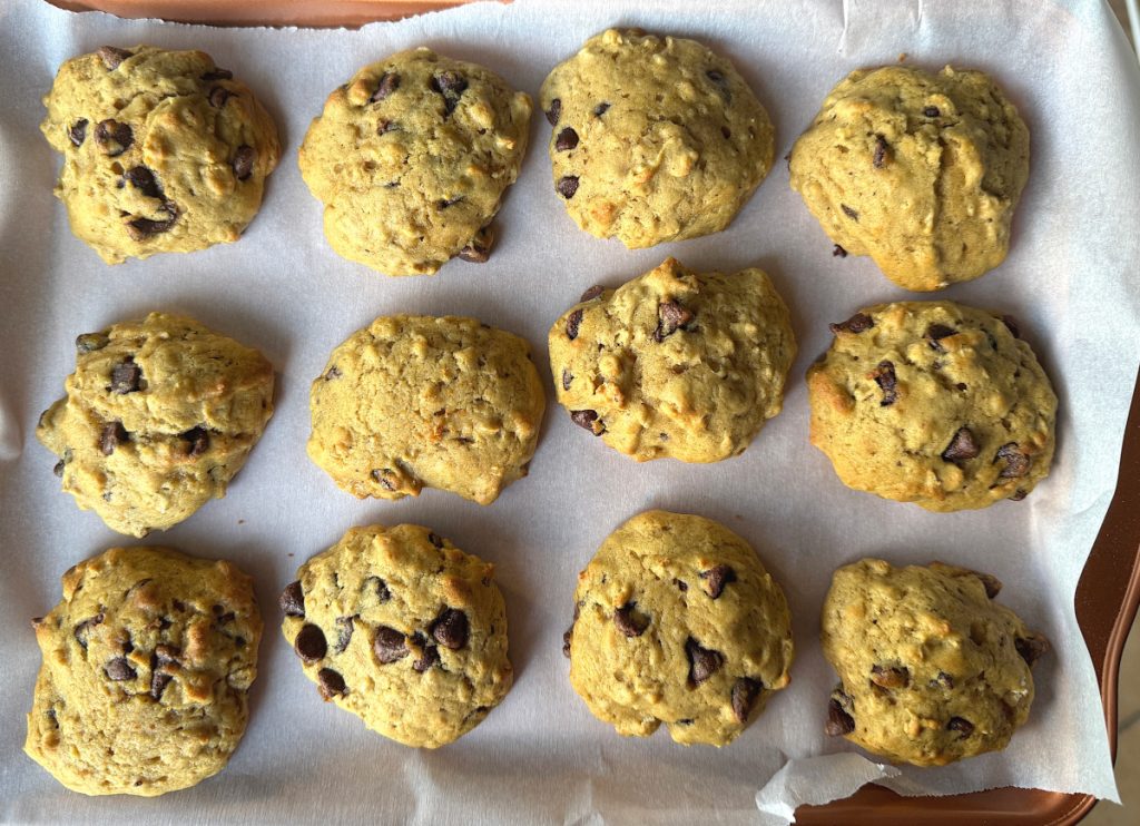 12 baked acorn squash chocolate chip cookies on a parchment paper lined cookie sheet