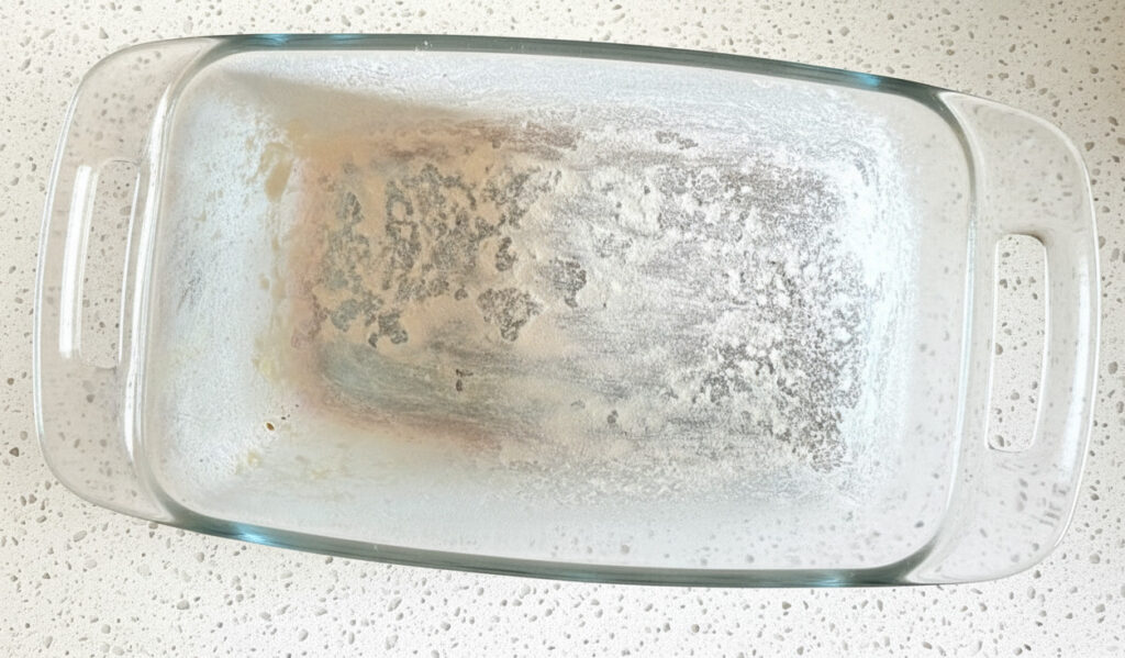 glass bread pan floured and buttered on a light colored granite countertop