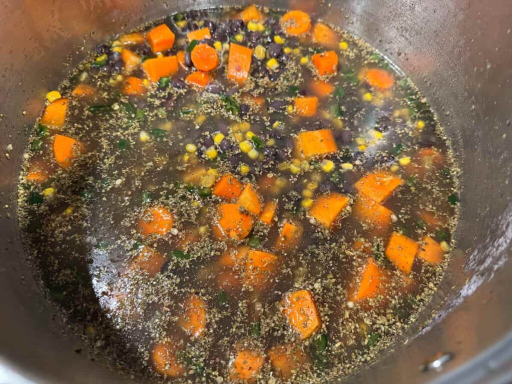 black bean soup with carrots and corn in a large stainless steel stock pot