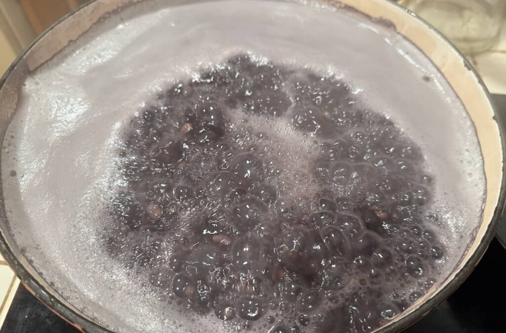 black beans boiling in a ceramic cast iron pot