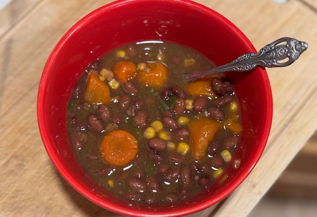 top view of a red bowl of black bean soup with a spoon in it