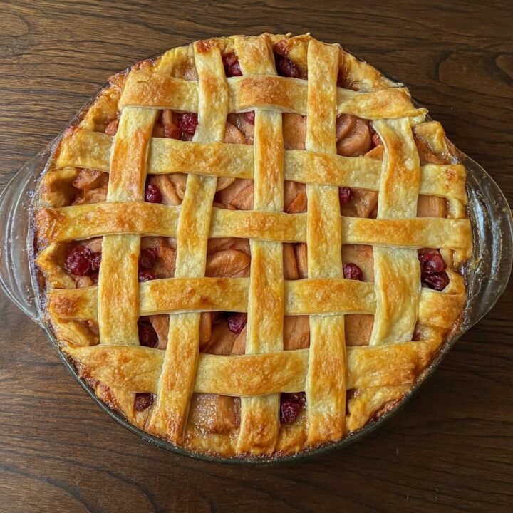 Apple cranberry pie with a lattice top on a wooden table