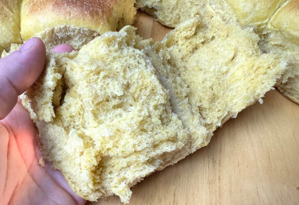 butternut squash dinner roll split in half being held by a hand