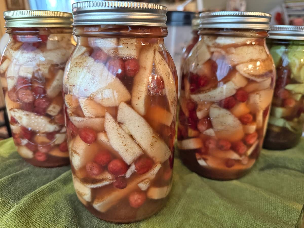 Jars of Apple Cranberry Pie Filling sitting on a green towel