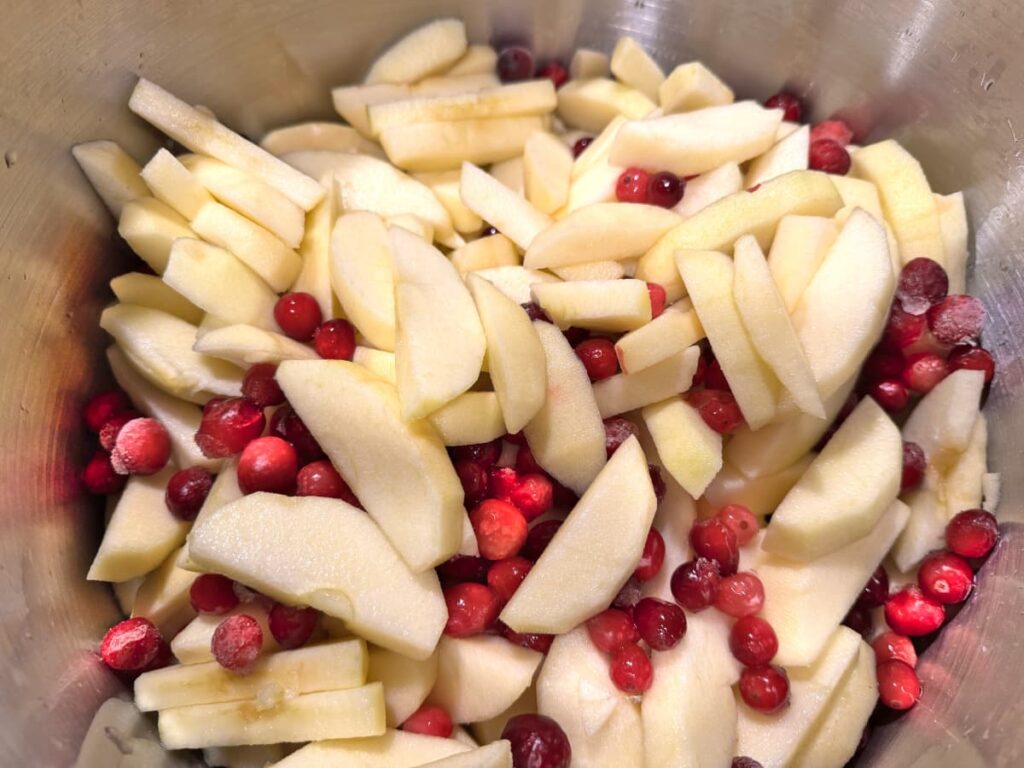 Apple slices and cranberries in a large stainless steel stock pot