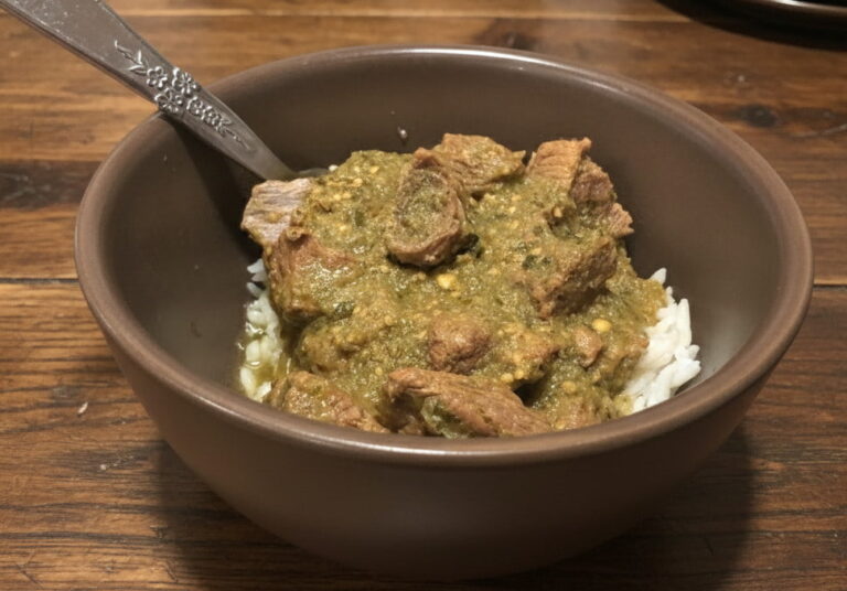 bowl of pressure canned pork chile verde on a wooden table with a spoon