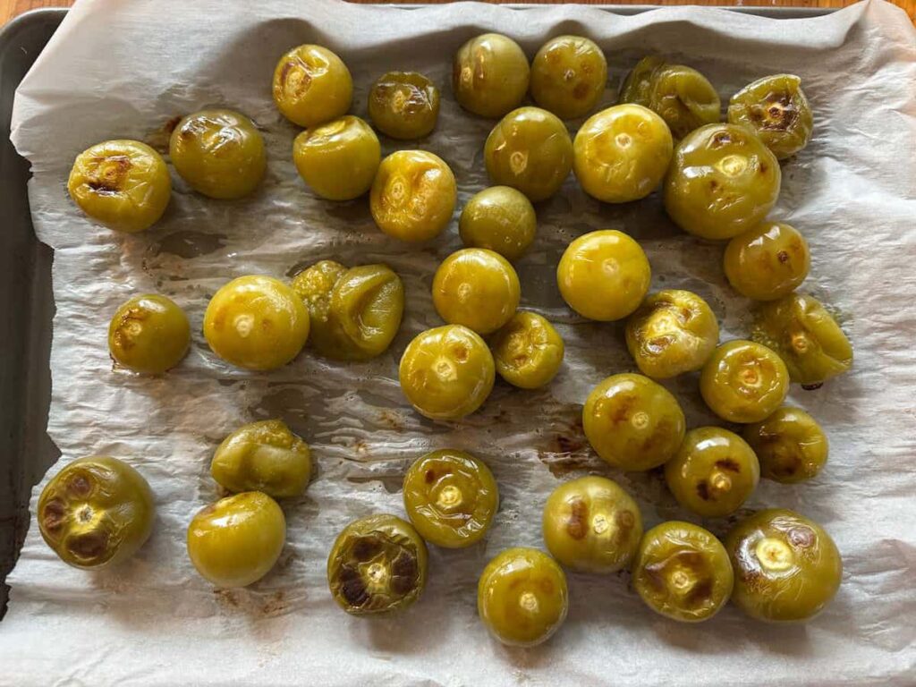 roasted tomatillos on a parchment lined baking sheet