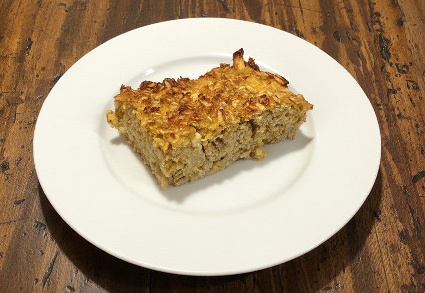 slice of apple butternut squash baked oatmeal on a white plate sitting on a wooden table