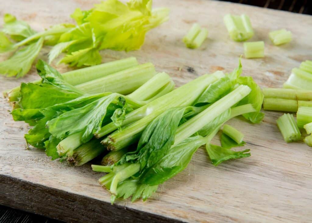 cut celery stocks on a butcher block cutting board